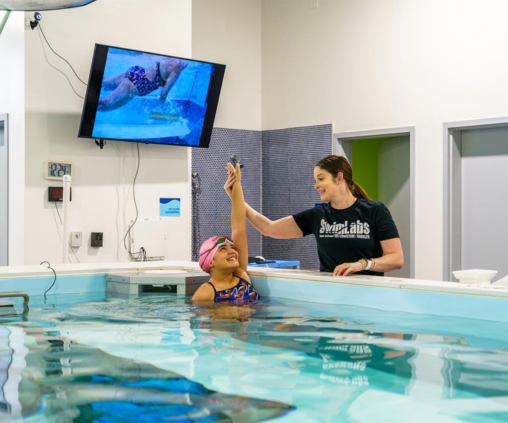 Swimming student high fiving instructor