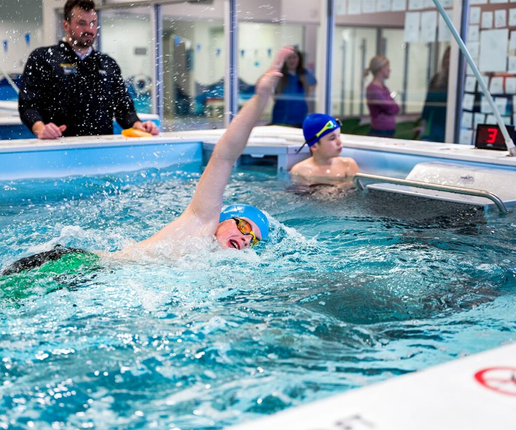 Student swimming in the water as instructor watches